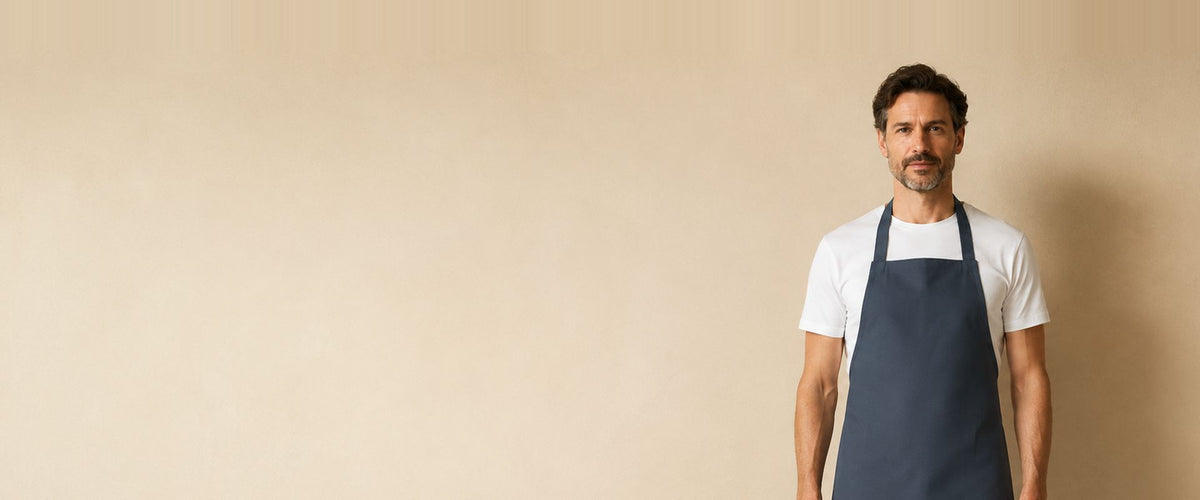 Homme en t-shirt blanc portant un tablier à bavette bleu ardoise.
