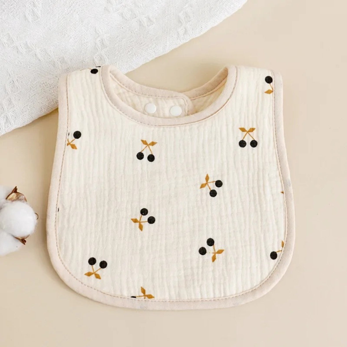 Bavette bébé en coton gaufré, motif imprimé sur fond écru, motif cerises, fond écru