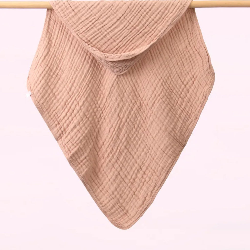 Tablier de bain bébé, la cape à capuche qu'on tend sur les bras, beige rosé, capuche dans un angle